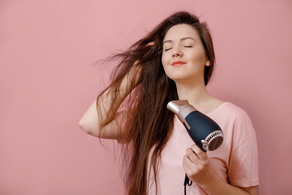 O cabeleireiro usa um secador de cabelo e modela o cabelo de uma